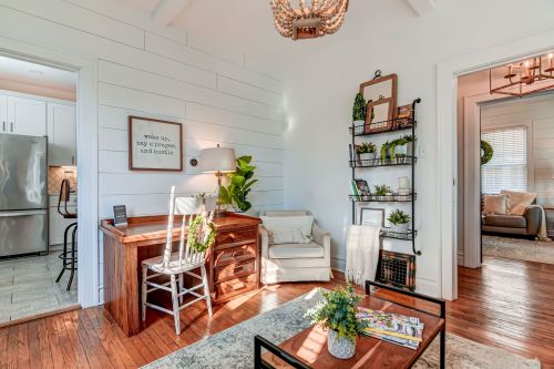 Cozy interior with a wooden desk, chair, and plants, featuring bright light and a welcoming atmosphere.