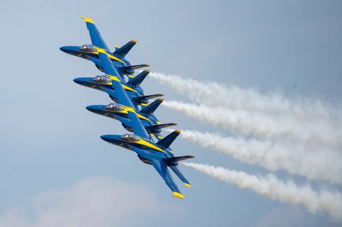 A formation of blue and yellow fighter jets flying in the sky, leaving trails of smoke behind them.