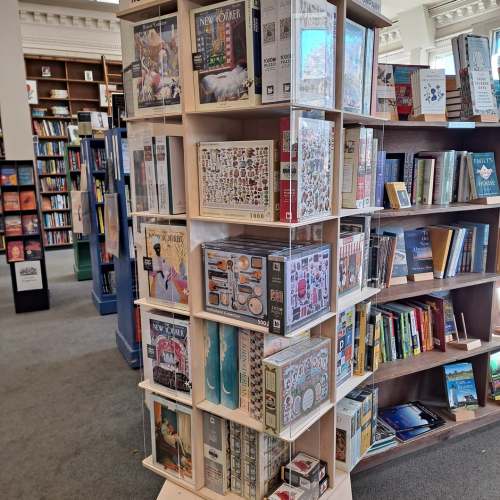 A display of various jigsaw puzzles featuring colorful designs in a bookstore.