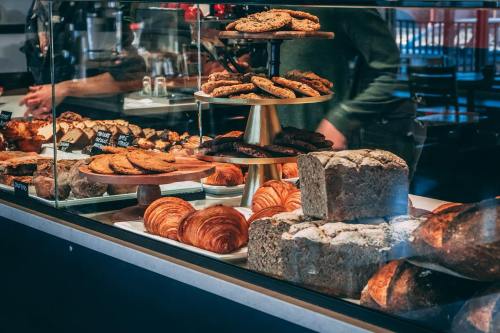A display case filled with various baked goods, including cookies, croissants, and loaves of bread.