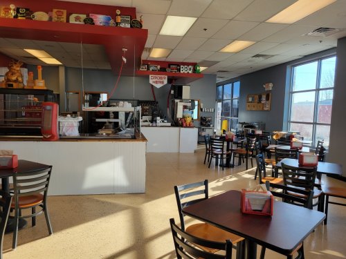 Bright, spacious restaurant interior with tables, a counter, and a BBQ sign, featuring a casual dining atmosphere.