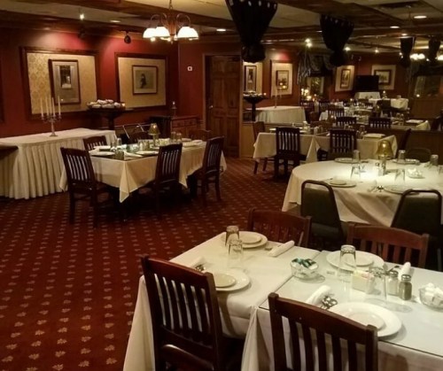 Elegant restaurant interior with neatly set tables, warm lighting, and classic decor.