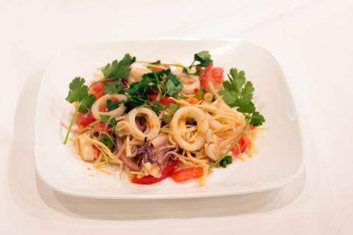 A plate of pasta with seafood, garnished with fresh herbs and tomatoes.