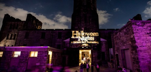 A spooky entrance to Halloween Nights at a historic stone penitentiary, illuminated against a night sky.