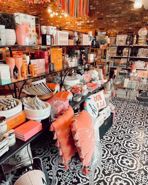 A vibrant store display featuring colorful home decor, pillows, and various gift items on patterned flooring.