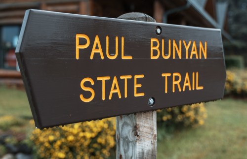 Sign for the Paul Bunyan State Trail, featuring bold yellow letters on a dark wooden background.