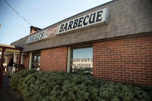 Exterior of Carlile's Barbecue, featuring a brick facade and a sign advertising fresh barbecue served daily.