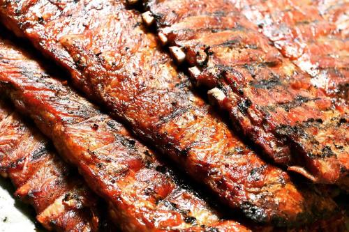 Close-up of grilled, smoky barbecue ribs with a caramelized glaze and charred grill marks.