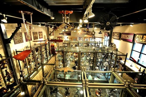 Aerial view of a vintage lighting museum filled with various antique lamps and fixtures displayed in glass cases.