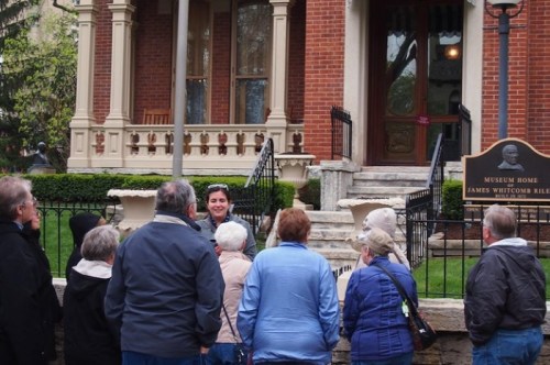 A tour guide speaks to a group of visitors outside a historic museum home.