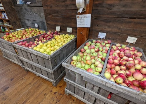 Two wooden crates filled with various types of apples in a rustic store setting.