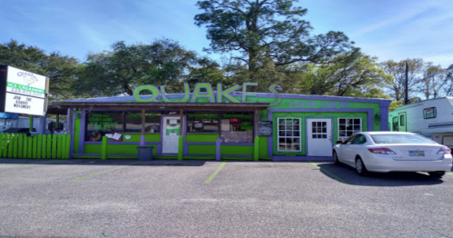 Colorful ice cream shop named "Quakes" with a green and purple exterior and a parked white car in front.