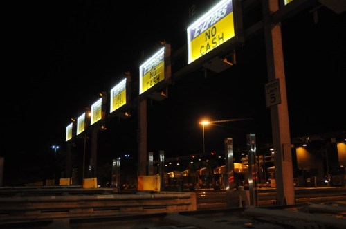 Toll booth at night with illuminated signs indicating "No Cash" and "Express" lanes.