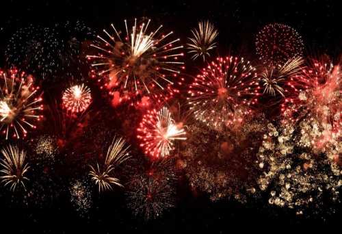 A vibrant display of red and gold fireworks illuminating the night sky in various shapes and patterns.