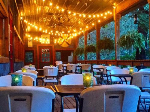 Cozy outdoor dining area with string lights, empty tables, and green candlelit centerpieces.