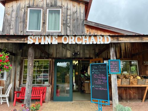 Entrance of Stine Orchard featuring a wooden facade, a chalkboard menu, and red benches outside.
