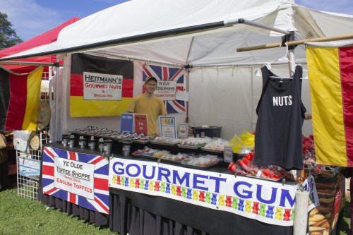 A colorful market stall selling gourmet nuts and toffees, featuring a sign and a display of various treats.