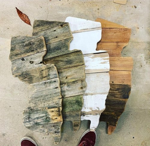 Three wooden cutouts of a state shape, each with different finishes: weathered, whitewashed, and natural wood.