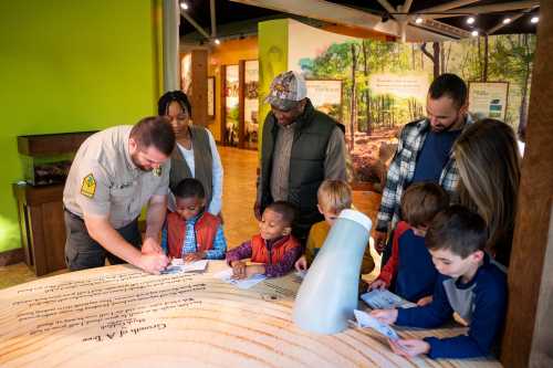 A park ranger teaches a diverse group of children and adults about nature at an educational exhibit.