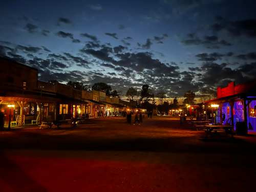 A western-style town at dusk, with colorful lights and a cloudy sky, creating a serene atmosphere.