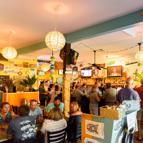A lively restaurant scene with patrons enjoying food and drinks, colorful decor, and hanging lanterns.