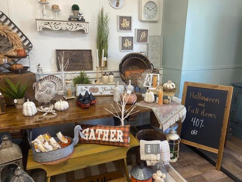 A cozy fall display featuring pumpkins, candles, and decor, with a sign advertising 40% off Halloween and fall items.