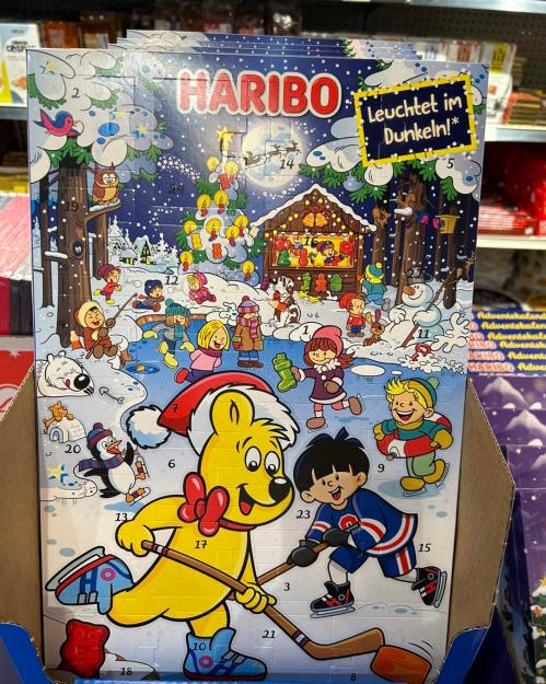 Colorful advent calendar featuring a bear skating, children playing, and a snowy scene with a festive cabin.