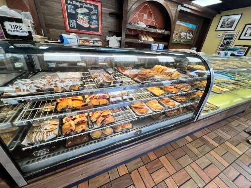 A display case filled with various baked goods, including pastries, cookies, and cakes in a bakery setting.
