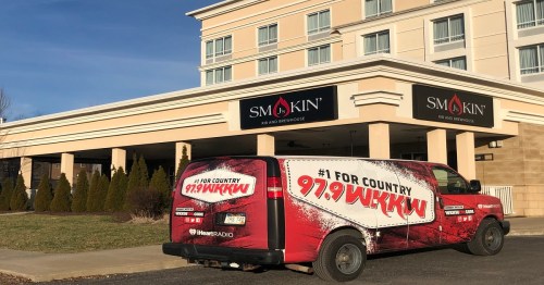A promotional van for 97.9 WKKW parked outside the Smokin' BBQ and Smokehouse restaurant.