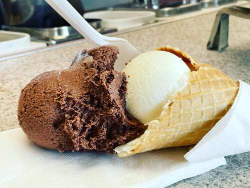 A waffle cone filled with chocolate and vanilla ice cream, resting on a napkin.