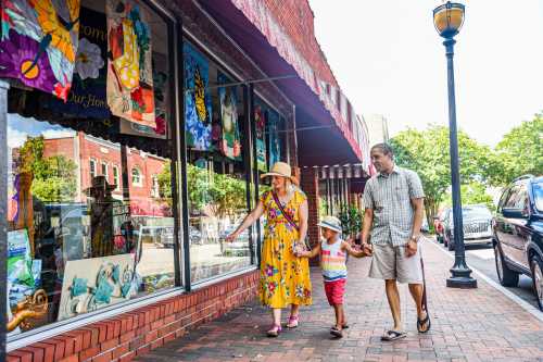 A family strolls along a colorful storefront, admiring window displays on a sunny day.