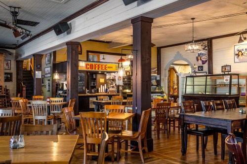 Cozy café interior with wooden tables, chairs, and a coffee counter, featuring warm lighting and vintage decor.