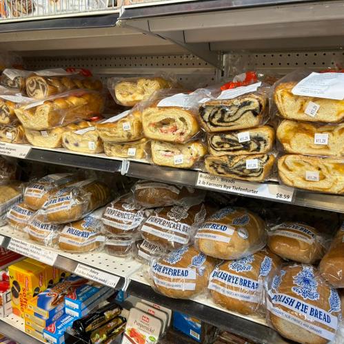 A display of various types of sweet and savory bread rolls and pastries on store shelves.