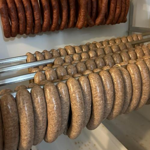 A display of sausages hanging on metal rods, with a variety of colors and textures.