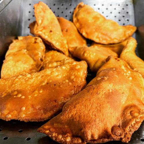 A close-up of golden-brown, crispy pastries piled in a metal strainer.