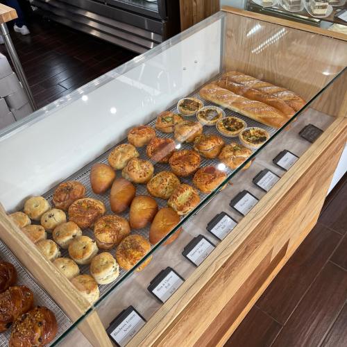 A display case filled with various freshly baked pastries and bread, including rolls and savory items.