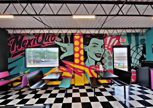 Colorful restaurant interior featuring a vibrant mural and retro-style seating with a checkered floor.