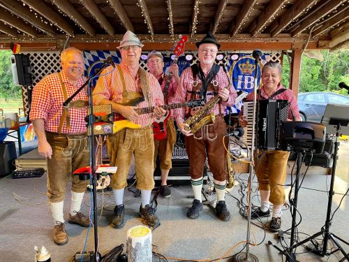 A lively band in traditional attire performs with various instruments at a festive outdoor venue.