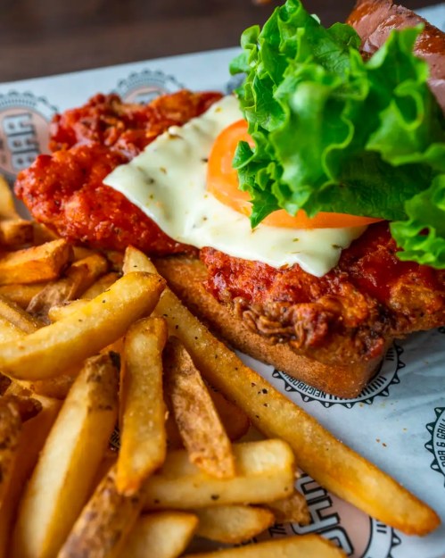 A crispy chicken sandwich topped with lettuce, tomato, and cheese, served with a side of golden fries.