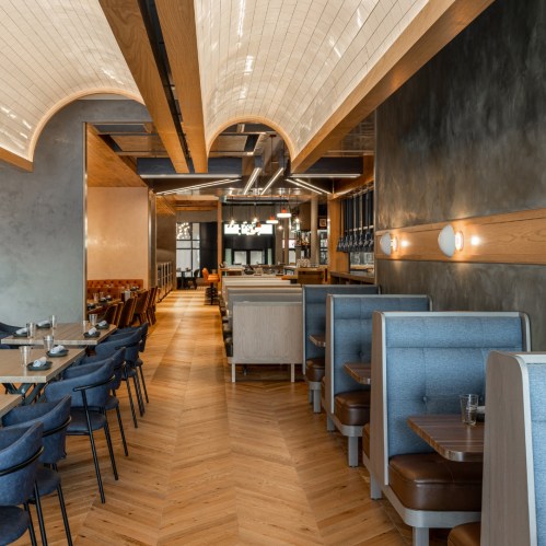 Modern restaurant interior featuring wooden accents, cozy booths, and a spacious dining area with stylish lighting.