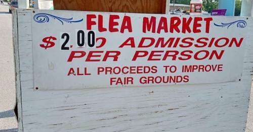 Sign for a flea market stating $2.00 admission per person, with proceeds going to improve fairgrounds.