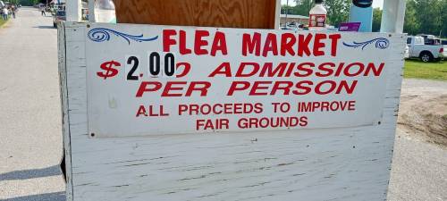 Sign for a flea market stating $2 admission per person, with proceeds to improve fairgrounds.