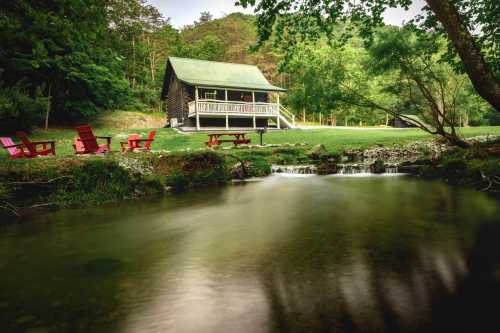 A cozy cabin by a stream, surrounded by greenery, with colorful chairs and a peaceful outdoor setting.