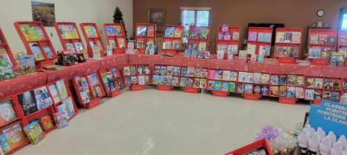 A colorful display of books arranged on red stands in a spacious room, with festive decorations in the background.
