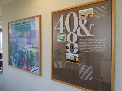 Two informational panels on a wall, featuring text and images about rail cars and post-WWII landscape changes.