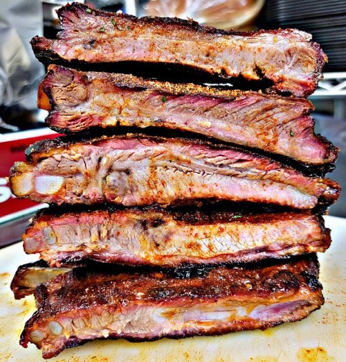 A stack of perfectly cooked, smoky barbecue ribs with a rich, caramelized crust and juicy meat.