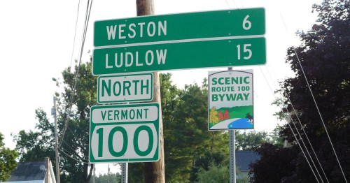 Green road sign indicating distances to Weston (6 miles) and Ludlow (15 miles) on Vermont Route 100, with a scenic byway sign.