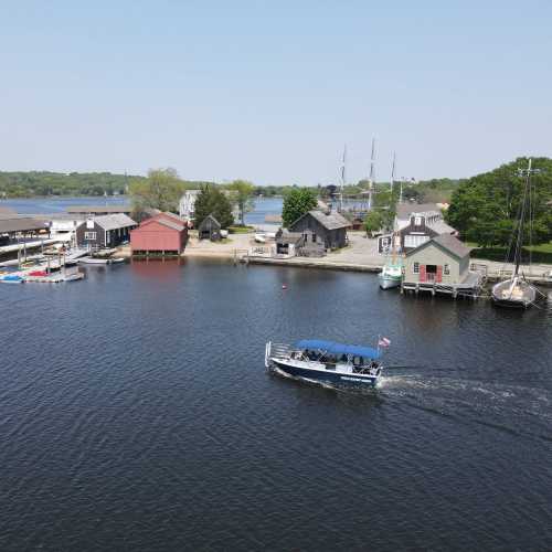 A scenic waterfront view with boats, colorful buildings, and lush greenery along the shore.