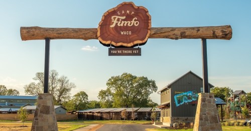 Sign for Camp Fimfo Waco, featuring a wooden log design and the phrase "You're There Yet" against a clear sky.