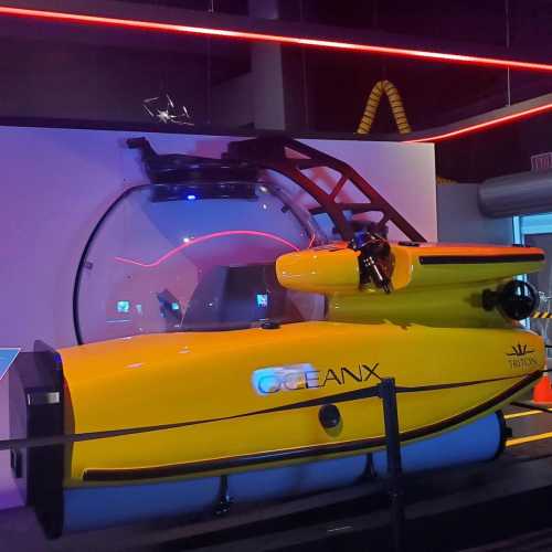 A bright yellow submarine displayed in a modern exhibit, featuring a large glass dome and sleek design.